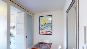 A small, bright room with a white table and chairs, a painting on the wall, and a door leading to a kitchen area. - Very spacious studio / city center (Parkview 4) (Zürich)