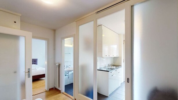 A modern hotel room with a bed, a small seating area, a bathroom with a sink, and a kitchenette. - Very spacious studio / city center (Parkview 4) (Zürich)
