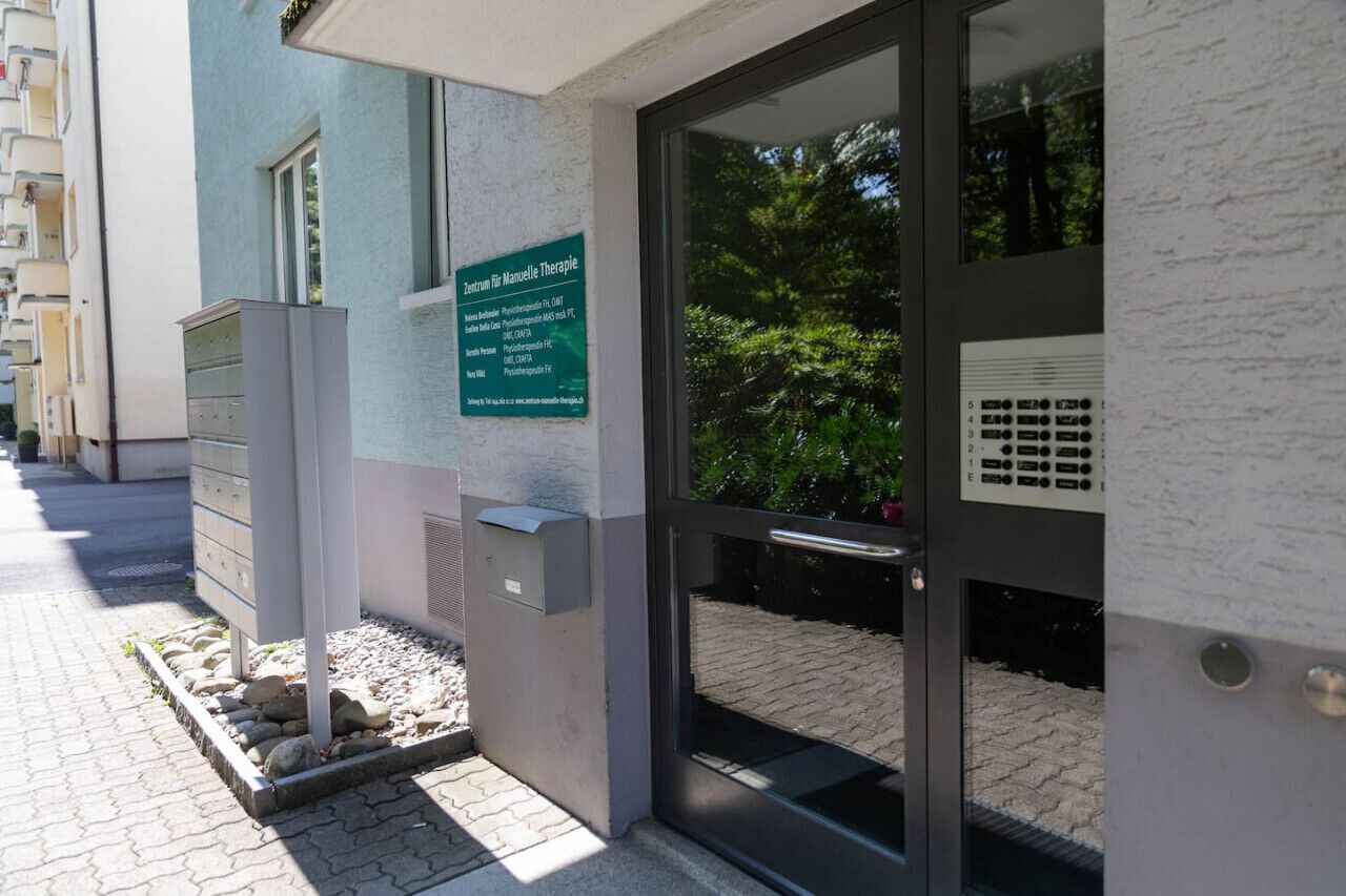 A building entrance with a sign for 'Zentrum für Naturopathie' and a glass door.