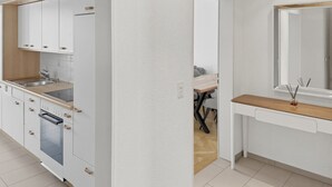 Una cocina moderna con armarios blancos, horno integrado y encimera de madera.