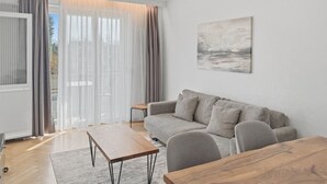 Una sala moderna con un sofá, una mesa baja de madera y vistas a través de un amplio ventanal.