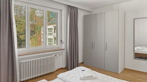 Una habitación de hotel con dos camas, un radiador, una ventana con cortinas y un armario.