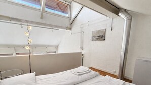 Une chambre avec deux lits, une fenêtre, un radiateur et un tableau accroché au mur.