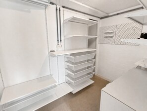 A white interior with a built-in shelving unit and a pegboard wall.