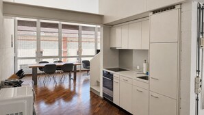 Une cuisine moderne avec des meubles blancs, un four encastré et un coin repas comprenant une table et des chaises.