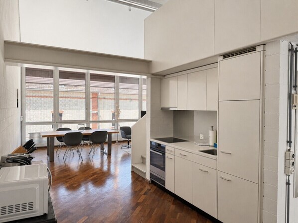 A modern kitchen with white cabinets, a built-in oven, and a dining area with a table and chairs.
