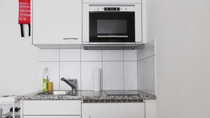 A kitchen with a built-in microwave, stainless steel sink, and a toaster. - Amazing Central Studio - Crown 32 (Zürich)