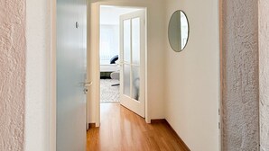A hallway with a wooden floor leading to a room with a bed and a window. - Amazing Central Studio - Crown 32 (Zürich)