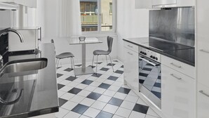 Una cocina moderna con piso de tablones en blanco y negro, electrodomésticos de acero inoxidable y armarios blancos.