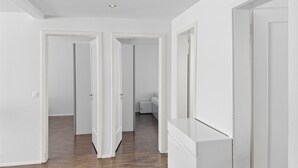 Un pasillo con piso de madera, paredes blancas y puertas blancas que dan a otras habitaciones.
