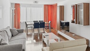 Una sala de estar moderna con sofá, mesa de centro, televisor y un comedor con sillas y mesa.