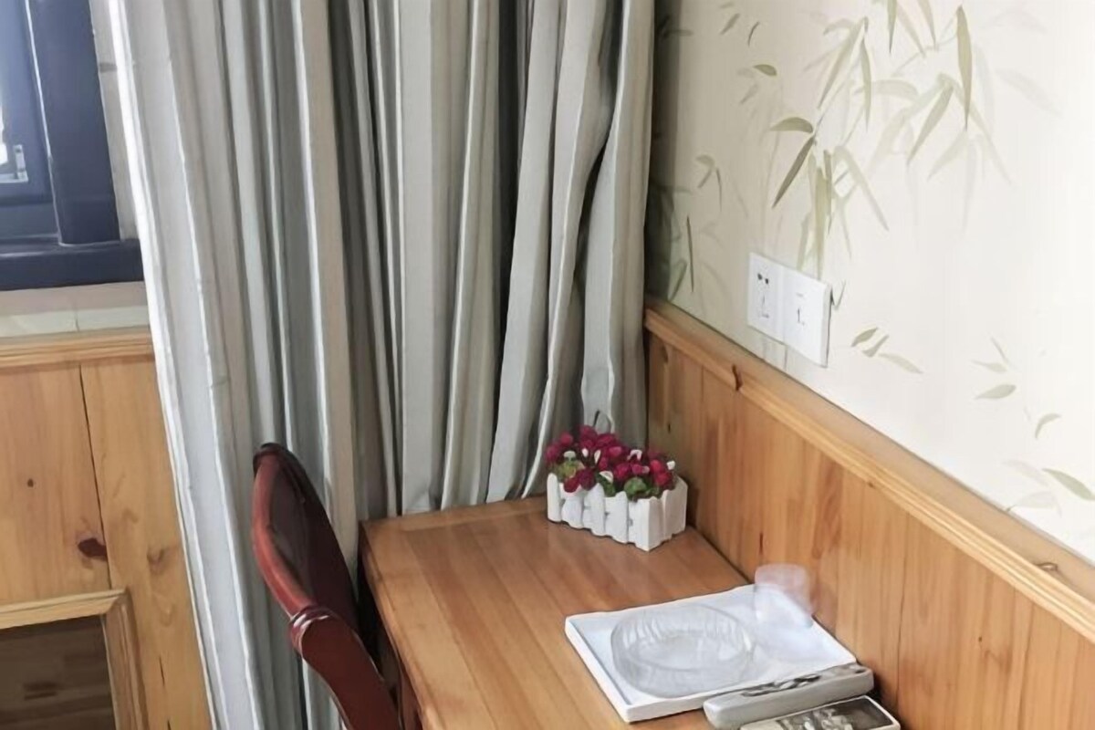 A wooden table with a white placemat, a small white box with flowers, and a wooden chair.