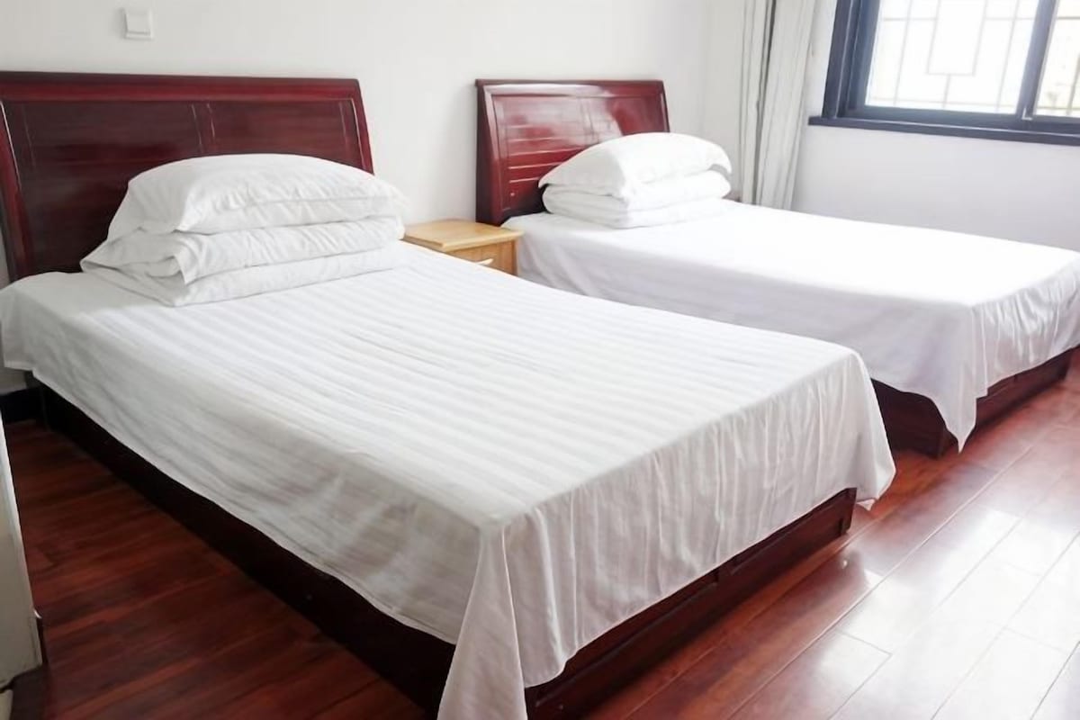 Two single beds with wooden headboards in a room with wooden flooring.