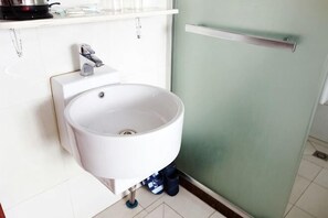 A white sink with a faucet, a towel rack, and a door with a handle. - Dongxiang Hostel (Shanghai)