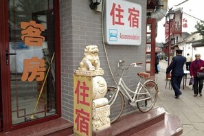 Un edificio tradicional chino con cartel de hotel, estatua de león y una bicicleta.