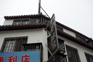 A building with traditional architectural elements, including a tiled roof and a balcony with a railing. - Dongxiang Hostel (Shanghai)