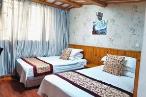 Quarto com duas camas, cabeceiras de madeira, parede estampada e janela com cortinas.
