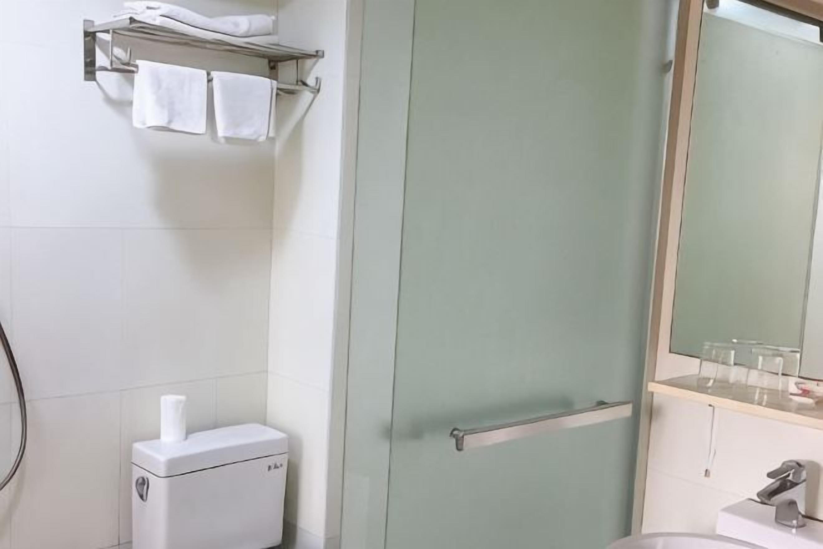 Une salle de bain équipée de toilettes, d’un porte-serviettes, d’un miroir et d’un lavabo.
