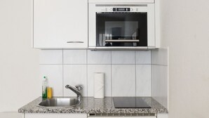 Een keuken met witte kasten, een roestvrijstalen spoelbak, een ingebouwde oven en een granieten aanrecht.