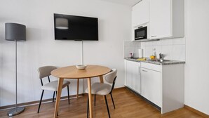 Eine moderne Küche mit weißen Schränken, einer Mikrowelle und einem an der Wand montierten Flachbildfernseher.