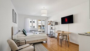Ein modernes, helles Zimmer mit einem Bett, einem Schreibtisch und einem Fernseher.