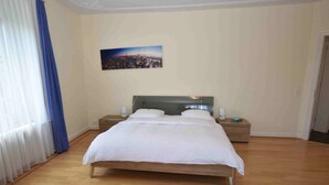 Un dormitorio con cama de madera, una mesita de noche y un cuadro de un paisaje urbano en la pared.