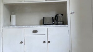 Uma cozinha compacta com armários brancos, bancada, torradeira e máquina de café.