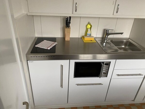 Compact kitchen with stainless steel appliances, sink, and microwave.
