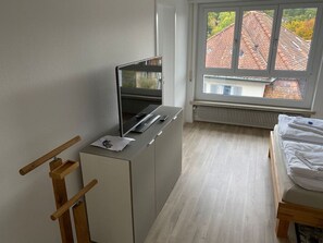Cozy retreat with a single bed, flat-screen TV, and storage.