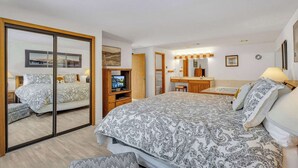 A bedroom with a large bed, a TV, a desk, and a bathroom. - Located in heart of Sunriver, complex pool access! (Sunriver)