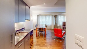 Een moderne keuken met een eethoek, met een houten tafel en rode stoelen.