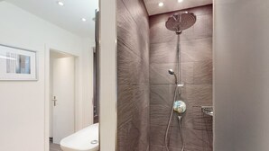 Een moderne badkamer met een douche, toilet en een foto in een lijst.