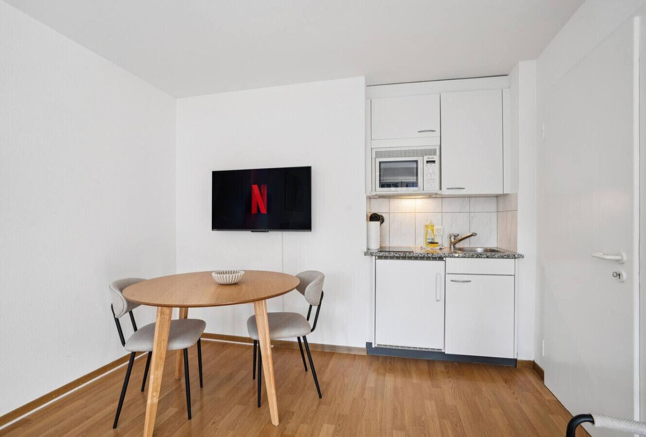Une cuisine de taille réduite avec des meubles blancs, un four à micro-ondes et un évier.