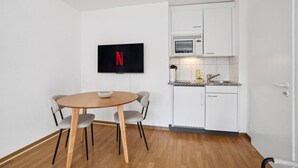 A compact kitchen with white cabinets, a microwave, and a sink. - Studio in the heart of Zurich (Crown 24) (Zürich)