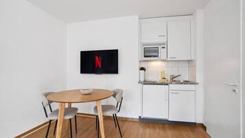 Une cuisine de taille réduite avec des meubles blancs, un four à micro-ondes et un évier.