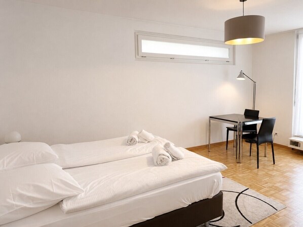 A bedroom with a bed, a desk, and a chair.