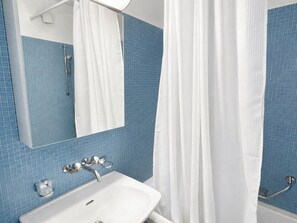 A bathroom with a white sink, a mirror, and blue tiled walls.