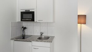 A compact kitchen with a built-in microwave, a sink, and a cabinet. - Lovely studio near center - Crown 1 (Zürich)