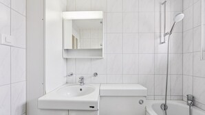 A modern bathroom with a white sink, mirror, toilet, and shower. - City-studio on top floor - Crown 48 (Zürich)