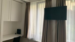 Quarto com escrivaninha, cadeira e televisão de tela plana na parede.