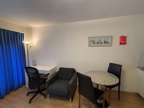 Cozy living space with a dining area, featuring a desk, table, and chairs.
