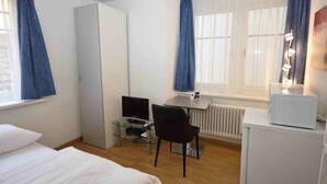 A hotel room with a bed, a desk with a computer, a chair, a wardrobe, and a radiator. - Studio at famous location  - Stork 21 (Zürich)