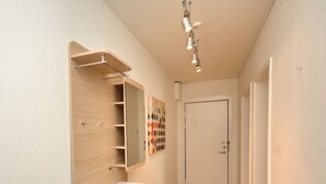 A hallway with a wooden vanity, a mirror, and a door at the end.