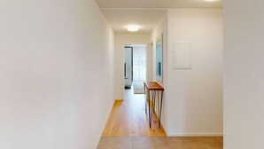 A narrow hallway with white walls, a wooden floor, and a small table with chairs. - Amazing big studio city center (Sun 7) (Zürich)
