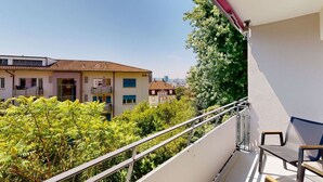 A balcony with a metal railing overlooking a garden and buildings. - Amazing big studio city center (Sun 7) (Zürich)