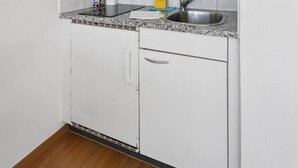 A compact kitchen with white cabinets, a microwave, a sink, and a countertop. - Very central studio (Crown 41) (Zürich)