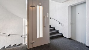 Ein modernes Interieur mit einer Treppe, einer Tür mit Griff und einer Wandleuchte.