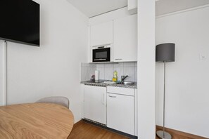 A compact kitchenette with a microwave, sink, and countertop.