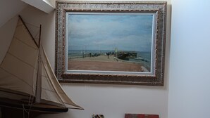 A sailboat model and a framed painting of a beach scene.
