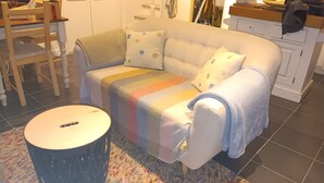 A living room with a sofa, a round table, and a colorful rug.